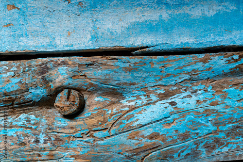 Close-up of weathered blue painted wooden planks with peeling layers, cracks and aged texture. Rustic surface ideal for vintage backgrounds and design use.