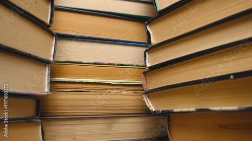 A close-up of stacks of old books. Three stacks of books with yellow and white pages.