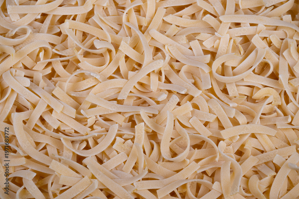 Fototapeta premium Detailed view of homemade egg noodles featuring rough textures and dusting. Closeup shot emphasizing handcrafted nature and textured surface of fresh egg noodles