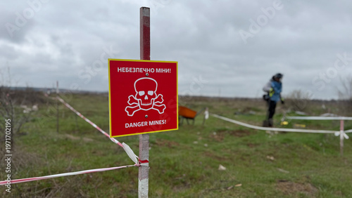 Photos Red warning sign with skull symbol and Ukrainian text “Danger Mines!” marking a hazardous minefield area in Ukraine