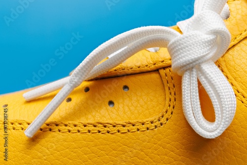 Vue macro extreme d'une basket jaune sur fond bleu uni