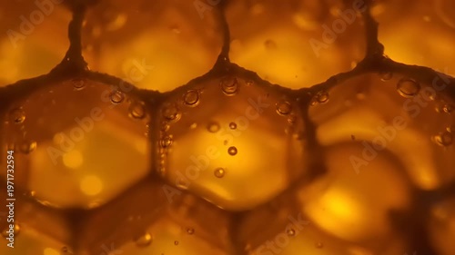 Golden honeycomb cells filled with liquid and bubbles up close