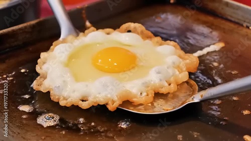 Cooking a sunny-side-up egg on a metal spoon over a baking sheet