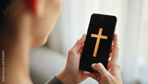 Person holds smartphone with wooden cross on black screen. Represents digital faith prayer and online religious service. Woman uses mobile for spiritual connection. Technology meets belief in faith.