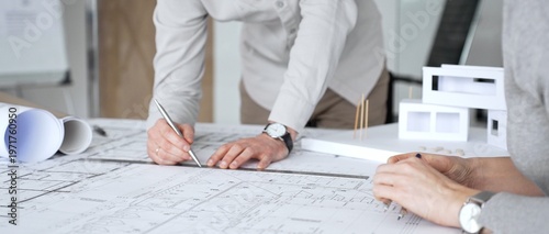 Cuadro en lienzo Architects are discussing building plans, using a compass over blueprints while