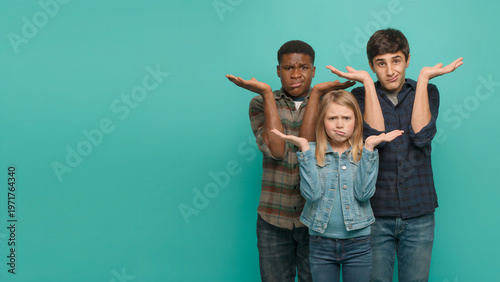 Group of young people shrugging with hands out in doubt against a turquoise background