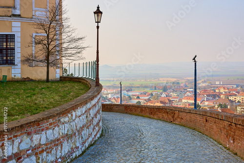 Quadro su tela Serene pathway by historic building overlooking quaint european village