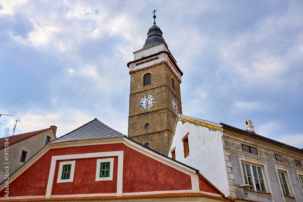 Fototapeta premium Historic clock tower and colorful buildings against cloudy sky