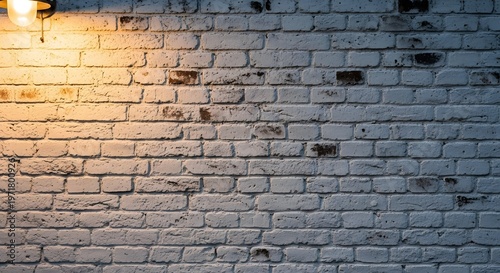 Vintage white brick wall illuminated by single outdoor lamp during evening hours
