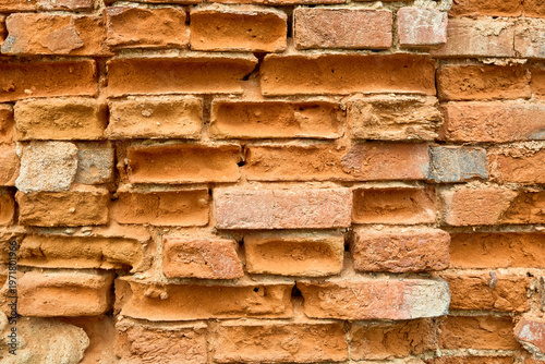 Canvas Print Weathered red brick wall with textured surface in urban setting