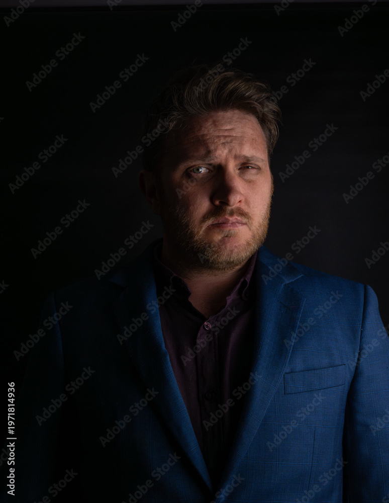 Obraz premium Suspicious expression portrait of man in suit looking sideways in dark lighting