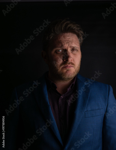 Valokuva Suspicious expression portrait of man in suit looking sideways in dark lighting