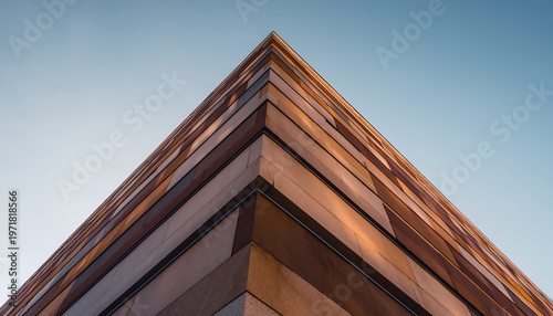 Modern building corner architectural detail with brown geometric panels against clear blue sky