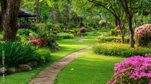 Lush, well-maintained parkland features a winding stone pathway bordered by vibrant flowering bushes and dense green foliage.