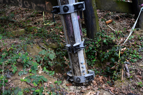 Cuadro en lienzo Galvanized iron pole splint, reinforcing metal with collar clamps on old wooden