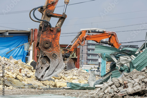 Bilde på lerret Excavator with heavy-duty demolition crusher works on concrete debris and scrap metal while another excavator in background busily clears rubble with hydraulic arm at demolition site