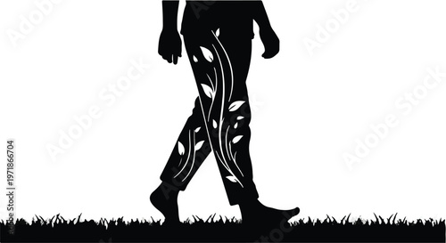 Silhouette of a person walking barefoot through grass with decorative leaves and vines adorning their pant legs.