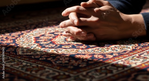 Hands praying on a colorful rug.