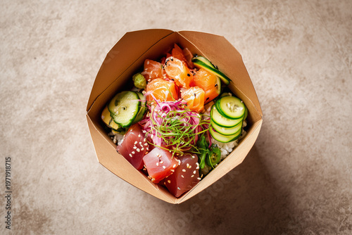 Top view of fresh poke bowl with salmon tuna avocado and vegetables in paper container creating healthy food and modern dining concept
