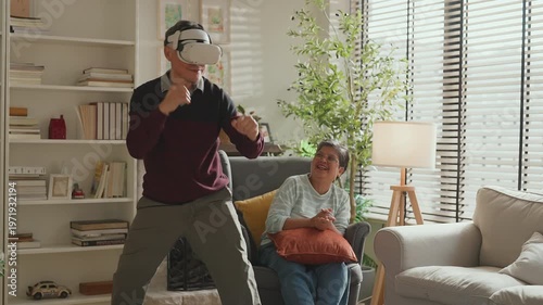 Senior Asian couple enjoying VR game experience in living room, elderly man and woman smiling while using virtual reality headset, fun technology activity, active lifestyle, modern entertainment at ho