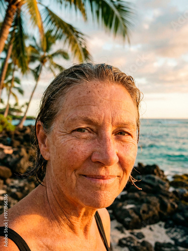 Homem maduro com cabelos molhados e regata preta em praia tropical com coqueiros e mar ao fundo ao entardecer