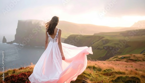 Woman in flowing gown gazes over coastal cliffs