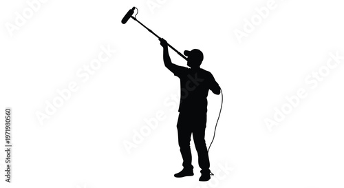 Sound recordist holding boom mic captured in a dramatic silhouette