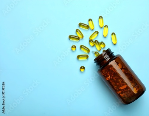 Amber bottle spills yellow gel capsules on bright blue surface