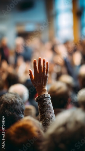 A raised hand with a bracelet in a blurred crowd conveys a sense of participation in a US election or vote with a hopeful mood