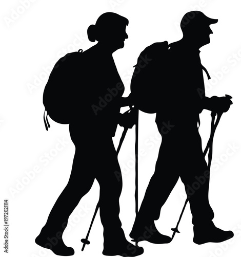 Silhouette of a senior couple hiking with backpacks and trekking poles, active lifestyle and outdoor adventure concept