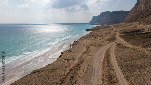 Drone view of desert coastal road by turquoise sea. Sokotra, Yemen.