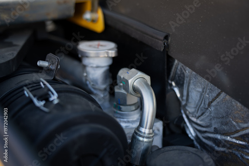 Fotografía Metal hydraulic fitting and service components within yellow construction equipm