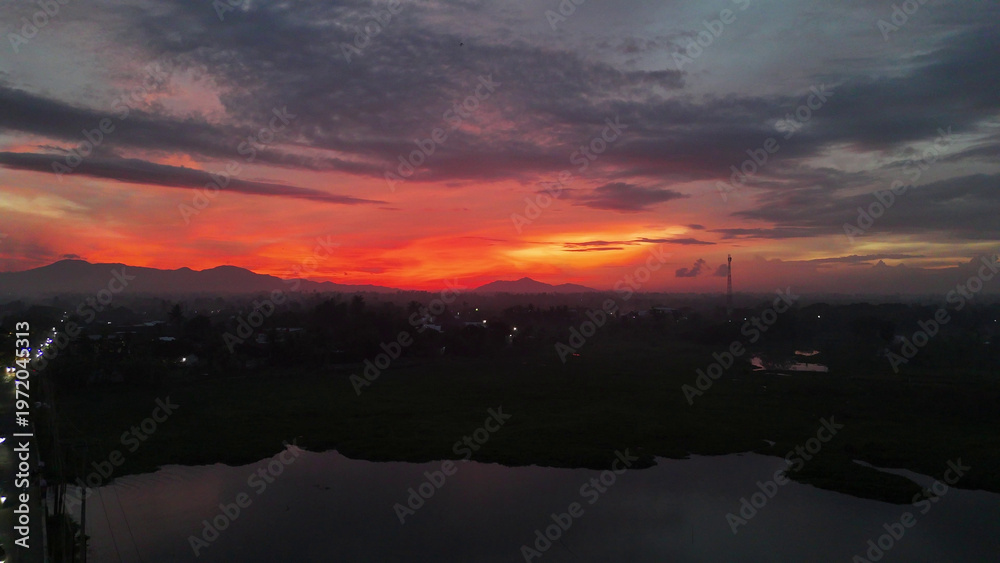 Fototapeta premium Dramatic Sunset Sky Over Mountains, Town, and River Landscape