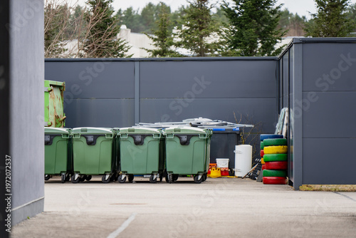 Obraz na płótnie Waste collection bins lined up in service yard near industrial fence, showing ur