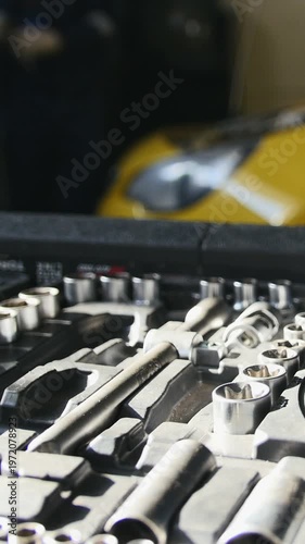 Mechanic repairs yellow car in professional auto service, de-focused time-lapse