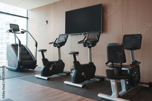 Foto Modern fitness gym featuring multiple exercise bikes and elliptical machines ind