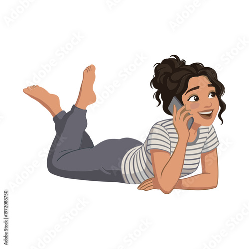 A woman lies on her stomach smiling while talking on the phone.
