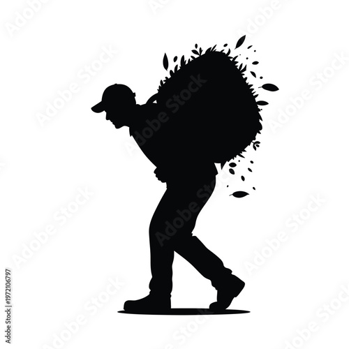 Silhouette of a man carrying a large load of leaves on his back