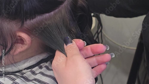 Hair styling at a beauty salon. The hairdresser uses a straightening iron.