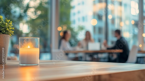 Office desk with lit candle and green plant, blurred business team background, modern workspace, professional environment, calm focus, work culture, ambient lighting.