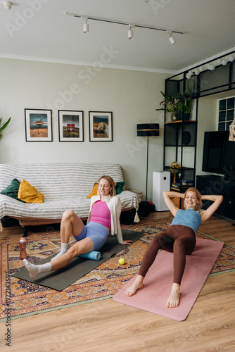 Obraz na plátně Two women are engaged in an energetic workout at home, smiling and motivating each other