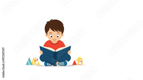 Young boy sitting cross legged on the floor while happily reading a large blue book with several toys scattered nearby in the room.
