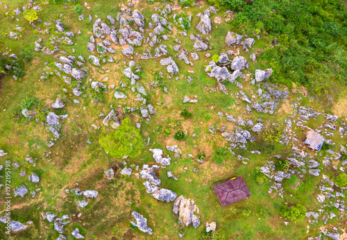 Top-down view of ancient rock formations scattered across green fields. Unique geological karst landscape with weathered limestone boulders, at Stone Garden, Padalarang, Bandung, Indonesia.