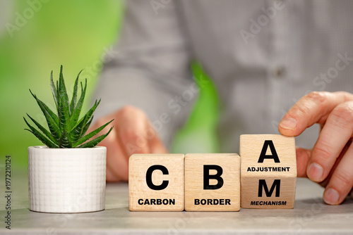 A man turns a wooden block with the symbol CBAM Carbon Border Adjustment Mechanism. A business environmental concept. The EU border carbon tax for imported goods.