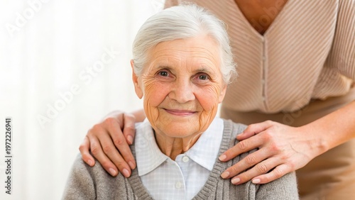 Mother Day Elderly woman smiles gently while a younger person places supportive hands on her shoulders in a warm, caring gesture.