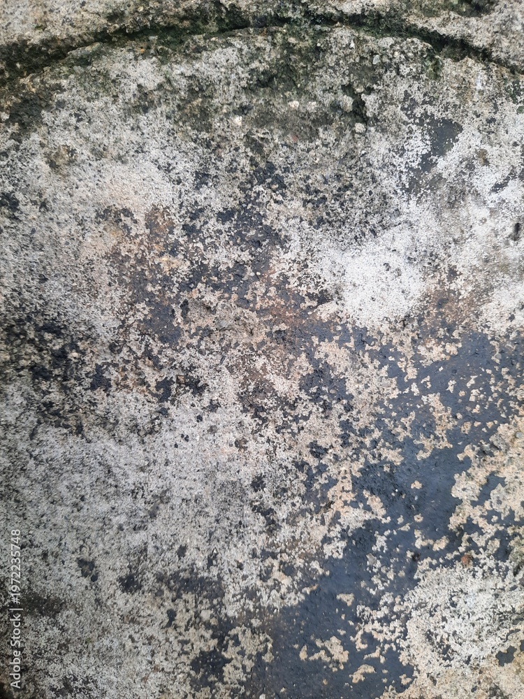 Fototapeta premium Close-up of weathered stone surface with dark natural texture and organic patterns formed over time, stone wall texture