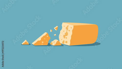 Large block of hard yellow cheese with small broken and crumbled pieces scattered on the side against a solid teal background.