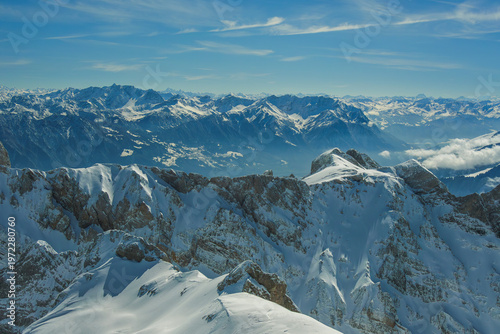 Snow covered mountain peaks under clear blue sky create breathtaking alpine landscape. vast expanse of rugged terrain and distant ranges evokes sense of awe and tranquility