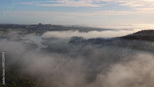 Aerial mist over farmland forest and inlet at sunrise New Zealand
