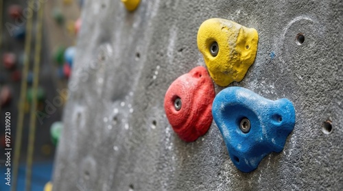 Close-up of colorful climbing holds on a textured artificial wall, highlighting a climber's grip and the challenge of indoor bouldering.